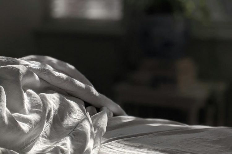 Layered bedding on a wooden bed frame